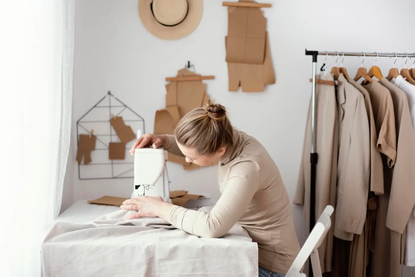 Seitliche Ansicht einer Schneiderin, die im Studio mit der Nähmaschine arbeitet.